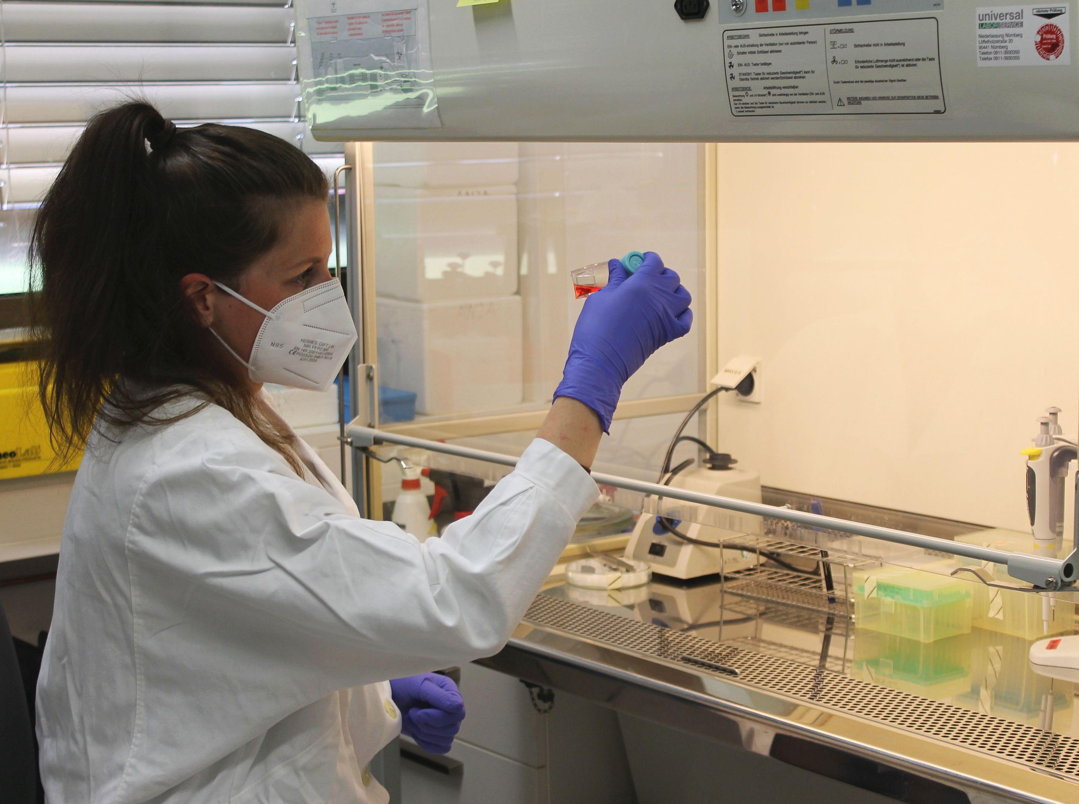 Anaja Ramsperger with a cell culture flask with red fluid in fornt of a cleanbench