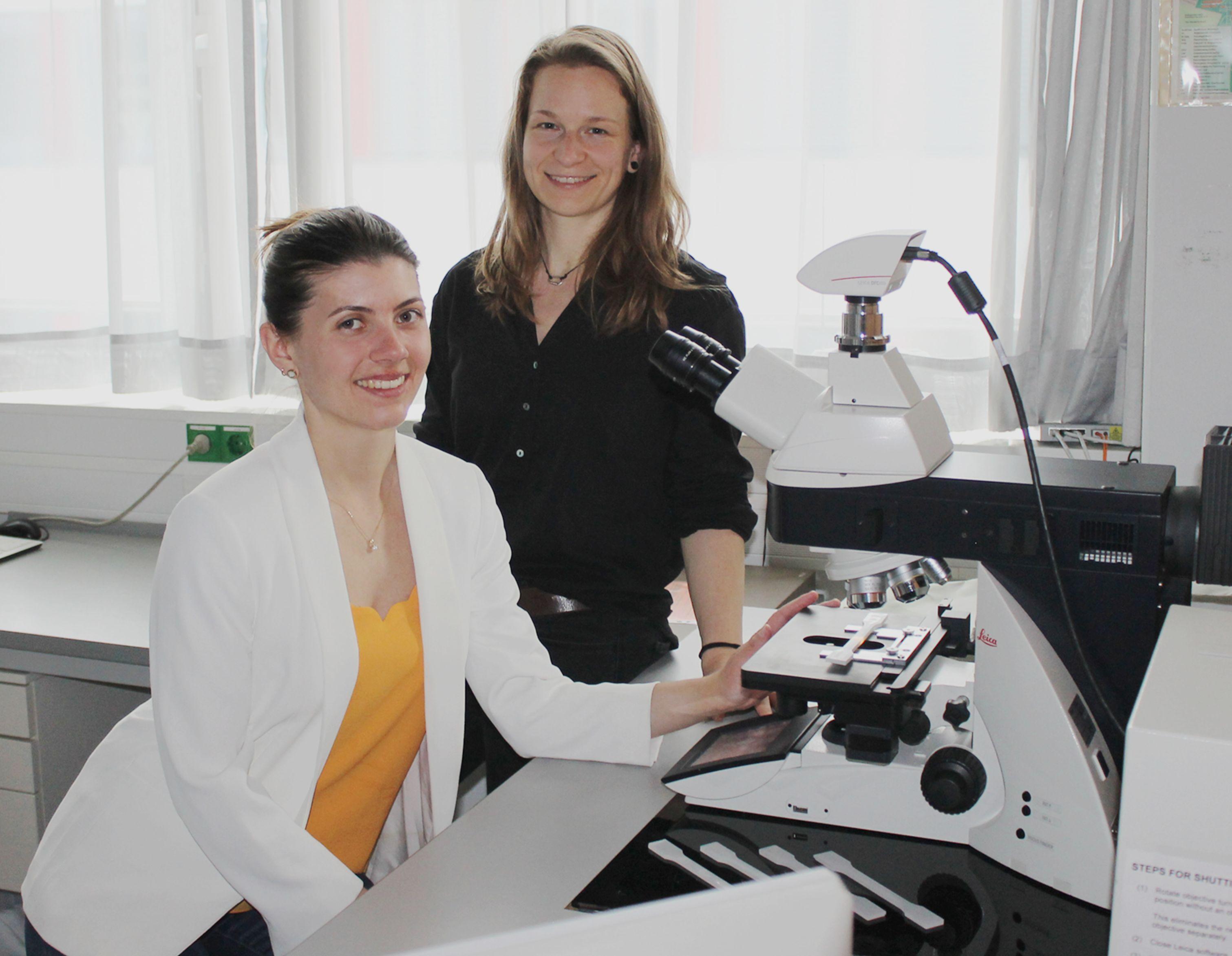 Die Bayreuther Doktorandinnen und Erstautorinnen Teresa Menzel (Polymere Werkstoffe) und Nora Meides (Makromolekulare Chemie) an einem Mikroskop, das bei der Analyse des Polyethylen-Abbaus zum Einsatz kam